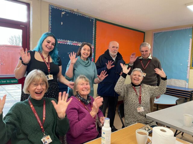 Hearing Help volunteers and visitors waving at a CDA drop-in session