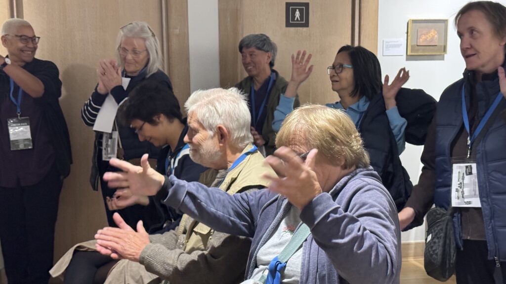 Cambridge Deaf Club members giving a BSL round of applause, waving their hands in the air, at Cambridge University Library